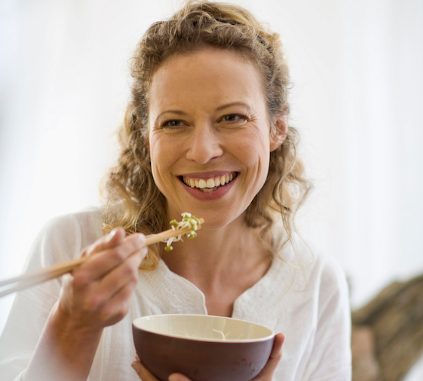 Mujer con sonrisa comiendo nuddles