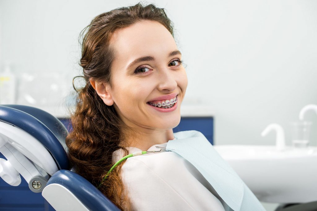 mujer sentada en silla dentista con aparatos dentales en ibiza