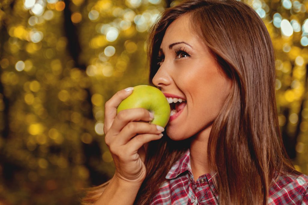 chica mordiendo manzana demuestra salud dental