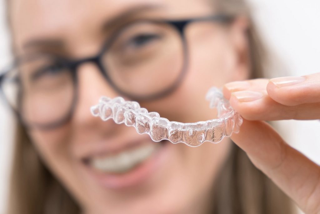 mujer con invisalign en la mano