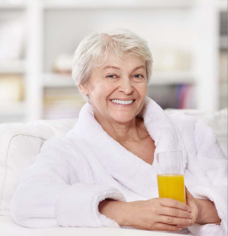 madre mayor en albornoz y un zumo en la mano con sonrisa bonita y perfecta