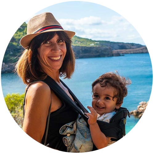 mujer sonriente con niño en ibiza y vistas al mar al fondo