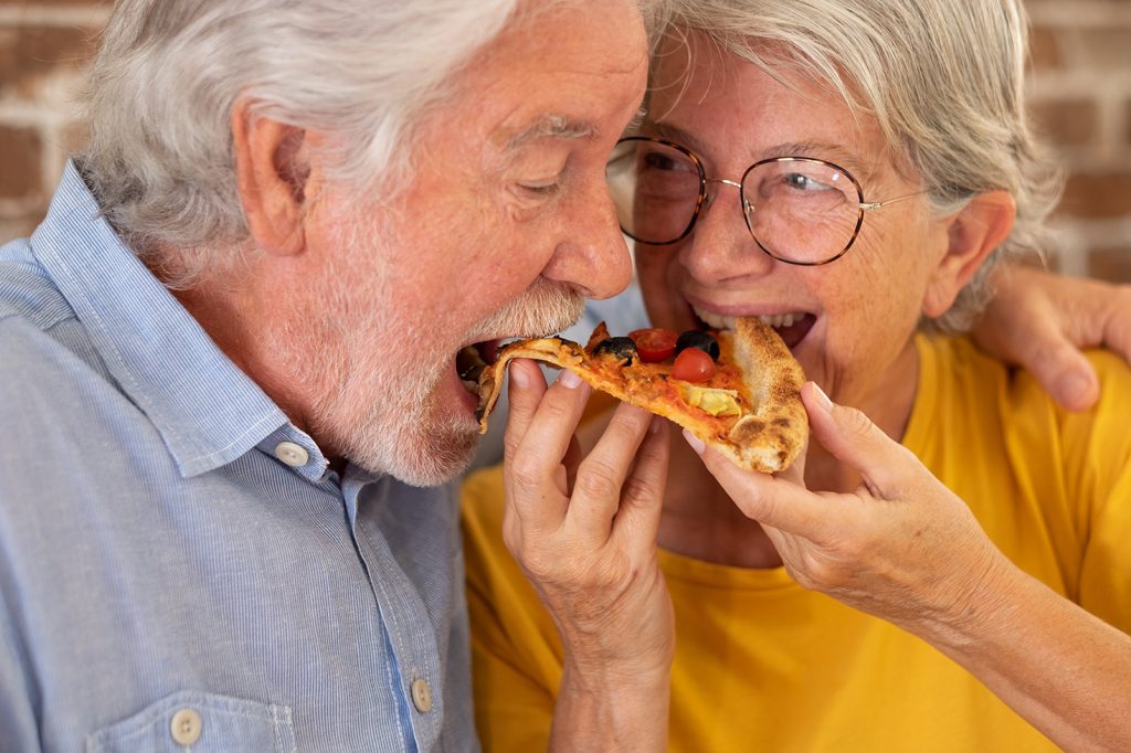 Hombre y mujer mayor comiendo pizza