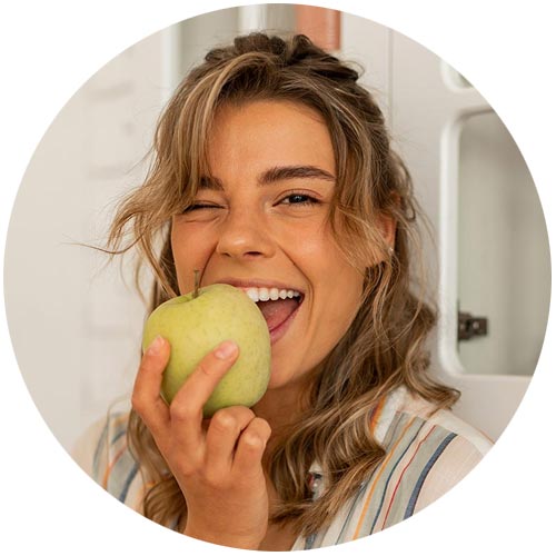 imagen mujer mordiendo manzana demostrando prevención y profilaxis dental